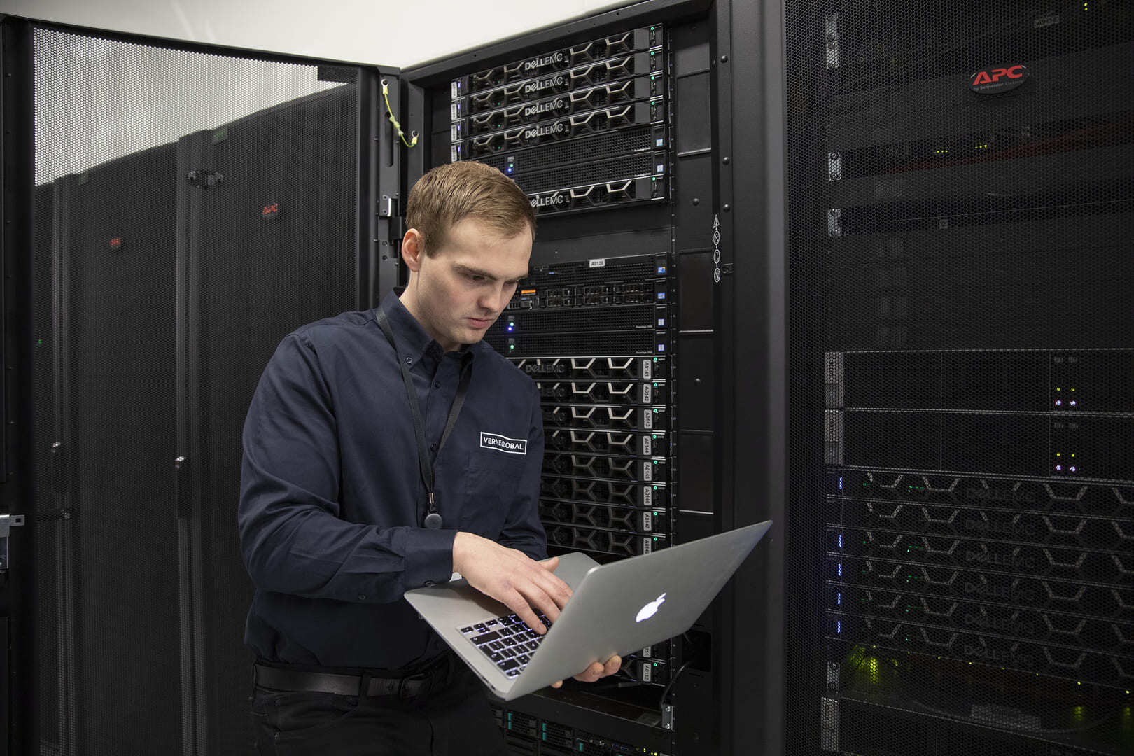 Verne engineer Oli using a laptop stood next to a server rack