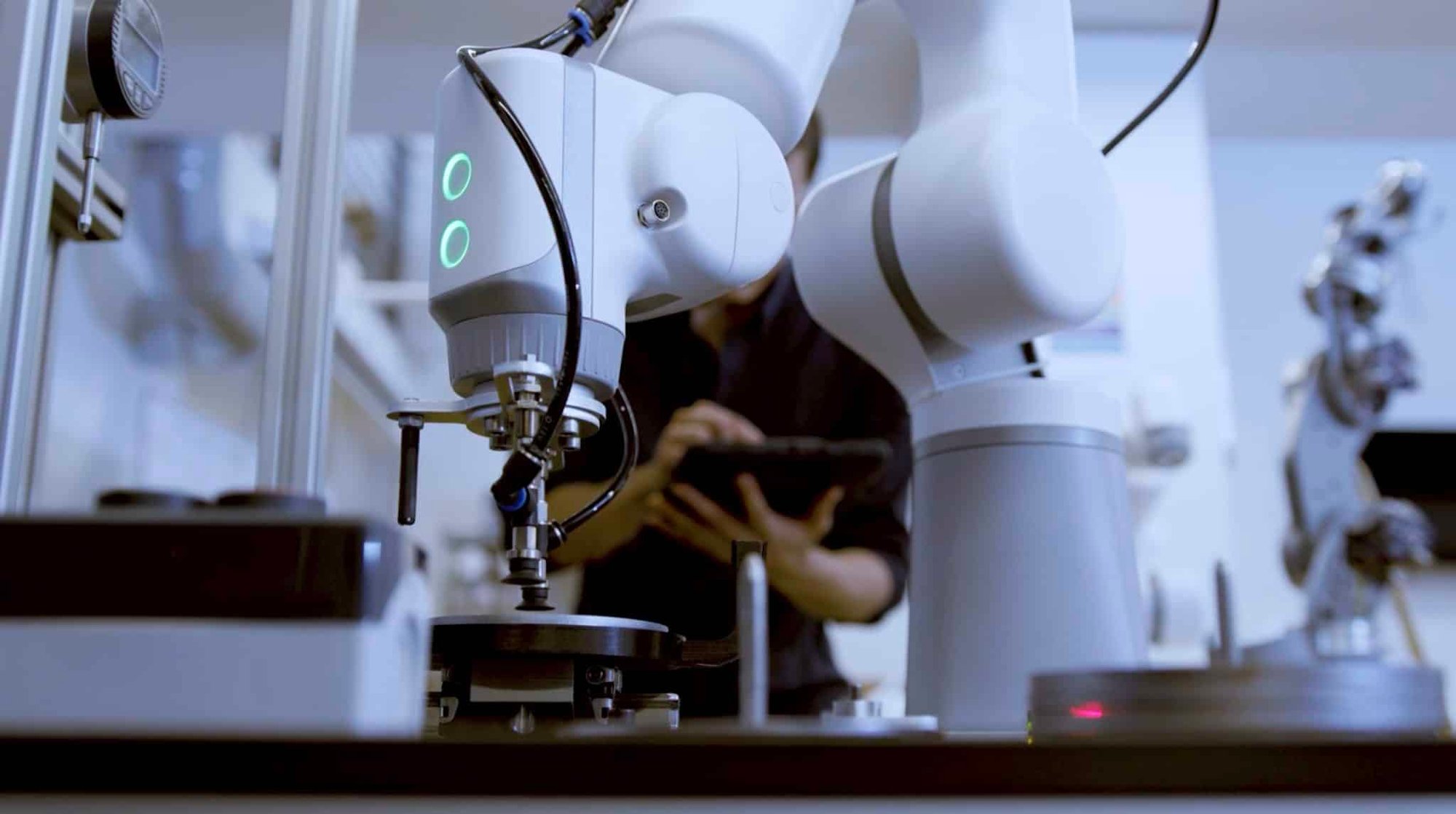 Robotic arm being monitored by an engineer using a tablet